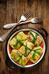 Cabbabge rolls, savoy cabbage stuffed rice and mushrooms in tomato sauce on wooden table, top view