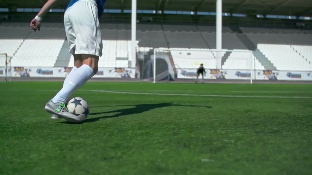 Soccer player running on green grass in stadium, kicking a ball and scoring a goal in slow motion