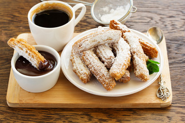 Churros with hot chocolate and powdered sugar.