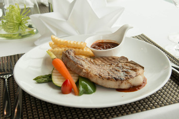  steak with pepper sauce on a plate together with vegetable