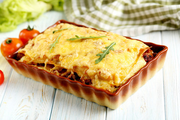 Italian lasagna in bowl on a blue wooden table