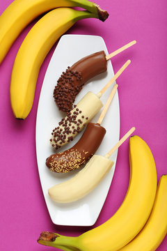 Banana covered in chocolate on a pink background