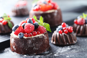 Sweet chocolate cakes with berries on black wooden table
