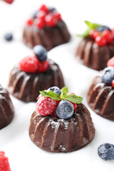 Sweet chocolate cakes with berries on white wooden table