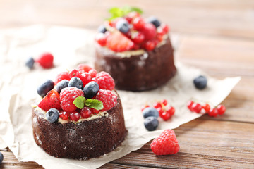 Sweet chocolate cakes with berries on wooden table