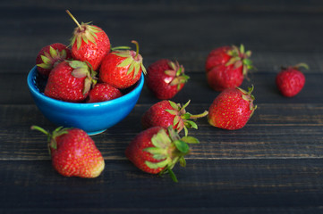 Fresh juicy berries of strawberry  in a blue small plateau on wooden table, closeup