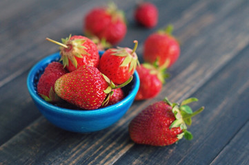 Fresh juicy berries of strawberry  in a blue small plateau on wooden table, closeup