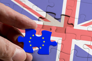 Hand holding piece of jigsaw puzzle with flag of European Union