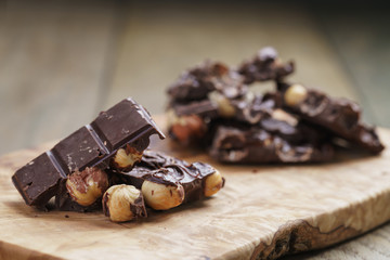 broken homemade bar of chocolate with cashew nuts on wood board