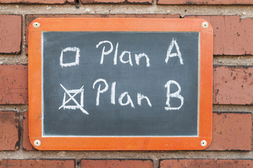 Tafel an einer Ziegelwand mit Text / Tafel an einer Ziegelwand mit Text Plan A, Plan B.