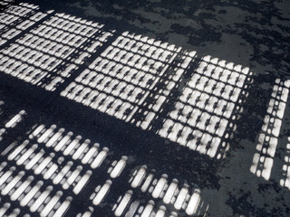 The shadow of the of the metal fence on the asphalt pavement deserted street