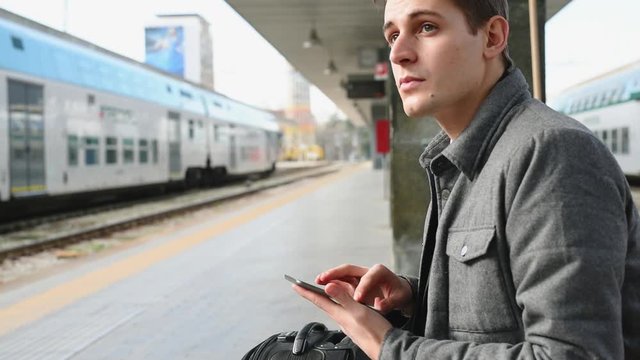 Using smart phone at railroad platform