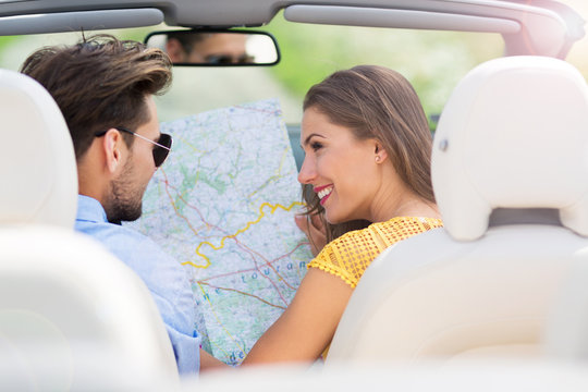 Couple Reading A Map While Sitting In The Car
