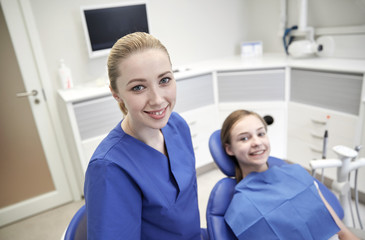 Obraz premium happy female dentist with patient girl at clinic