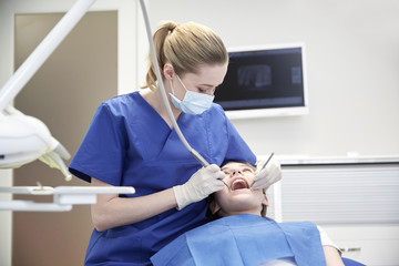 female dentist checking patient girl teeth