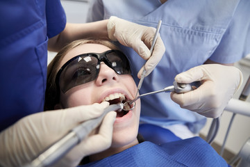 Fototapeta premium female dentists treating patient girl teeth