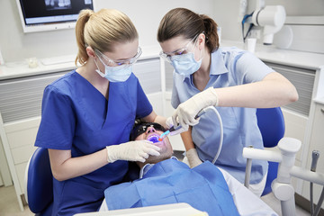 dentists treating male patient teeth at clinic