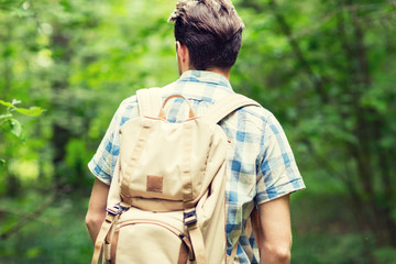 young man with backpack hiking in woods