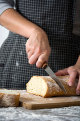 Woman cutting bread on rustic wooden table
