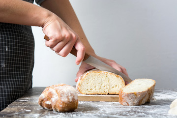 Woman cutting bread on rustic wooden table

