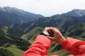 young woman hiker checking the altimeter on sports watch at mountain peak