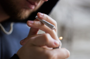 close up of addict lighting up marijuana joint - obrazy, fototapety, plakaty