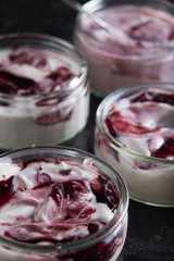 Yogurts with fruits assortment in glass bowls on dark marble background. Natural and fruit healthy, diet, gourmet dessert for granola breakfast. Sweet yoghurts closeup.