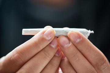 close up of addict hands with marijuana joint