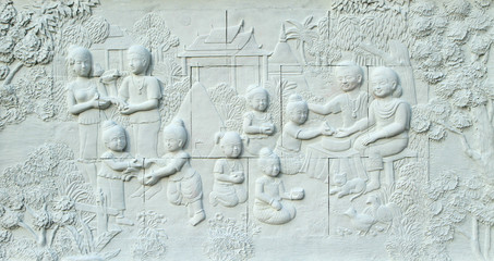 Stone carving of Thai culture Songkran festival on temple wall