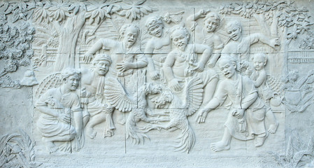Stone carving of Thai cockfighting sport on temple wall