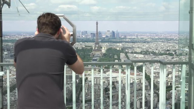 Young Man Observes Eiffel Tower On Top Of Montparnasse Tower, Paris. The Montparnasse Tower Panoramic Observation Deck has the most beautiful view of Paris