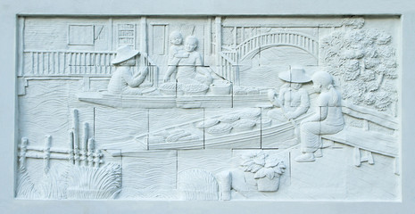 Stone carving of Traditional Thai floating market on temple wall