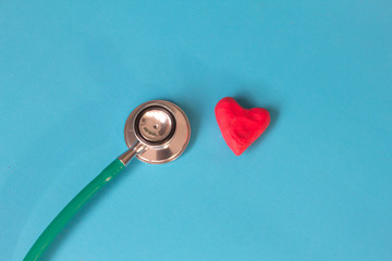 Red heart and a stethoscope on blue background