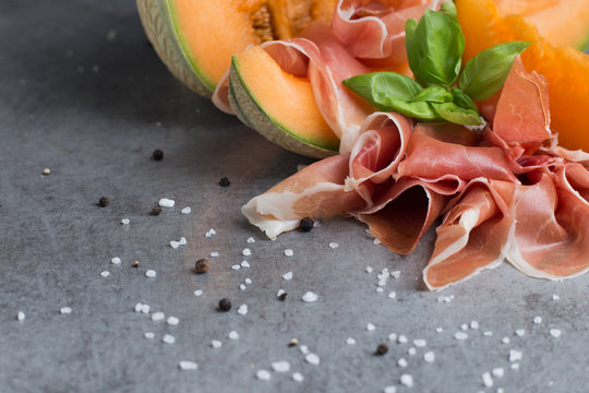 Jambon mix. Ham. Traditional Italian and Spanish salting, smoking, dry-cured dish - jamon Serrano and prosciutto crudo sliced with melon on grey background. Copy space. Closeup. 
