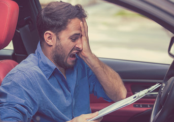 Stressed desperate man driver with papers sitting inside his car