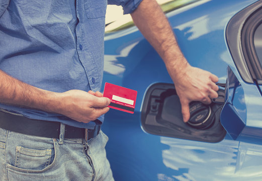 Man with credit card opening fuel tank of his new car