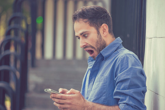 anxious man looking at phone seeing bad message or photos with disgusting emotion on face