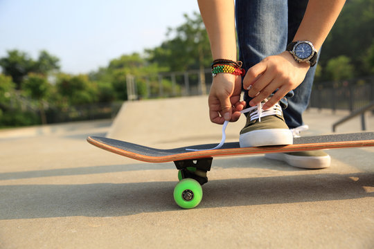 skateboarder tying shoelace at skatepark ramp