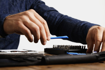 Professional takes speciall opening plastic instrument from his tool bag to repair tablet