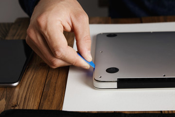Pro uses plastic opener tool to open case of broken computer laptop to fix it