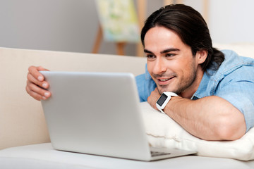 Positive bearded man using laptop