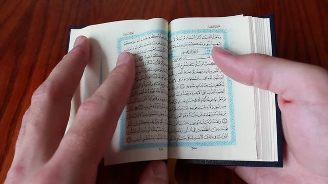 Man thumbs through the small Quran