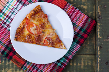 Piece of pizza Margarita on a wooden table