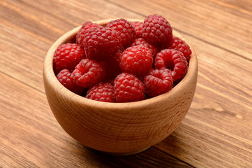 Ripe raspberries in wooden bowl. Close-up.