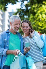 Smiling couple using mobile phone in city