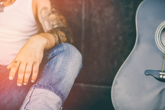 Hipster  with tattoos and guitar. Lens flare added.