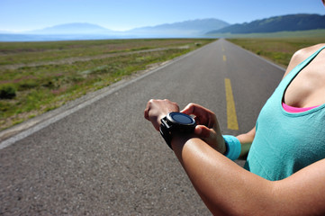 young woman runner ready to run set and looking at sports smart watch, checking performance or heart rate pulse trace. sport and fitness outdoors .