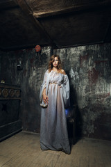 Pretty mystic lady in gothic white dress in underground dungeon