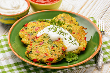 Vegetarian cuisine - vegetable fritters (with potatoes, carrot, zucchini, paprika and parsley) served with yogurt sauce.