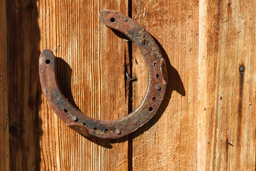 Rusty horseshoe on old wooden background. Outdoors image on a sunny day.